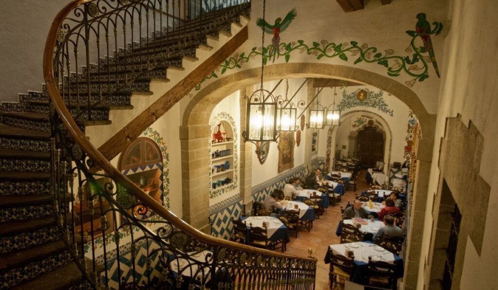 restaurante estilo colonial con varias mesas y unas escaleras