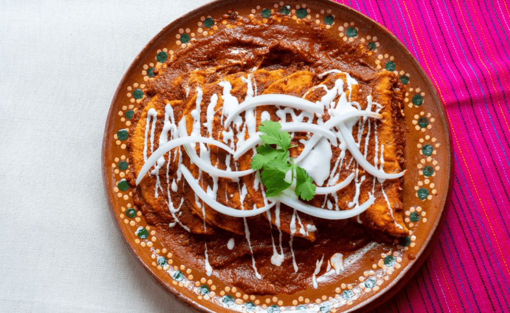 tacos estilo tlaquepaque servidos en un plato de barro, bañados por salsa roja